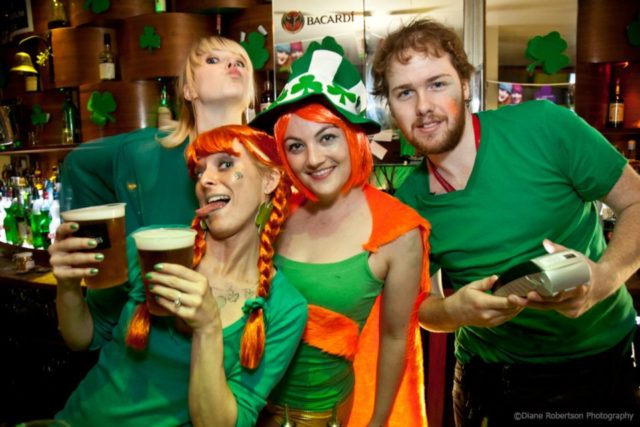 Des personnes fêtant la Saint Patrick, habillés en vert avec des pintes de bière à la main